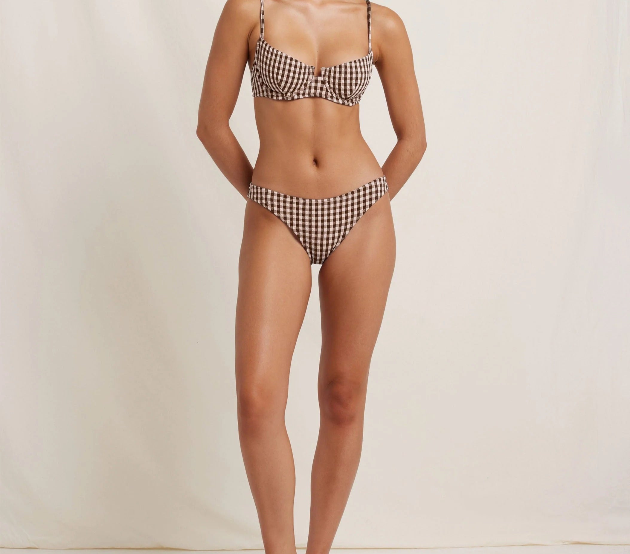 Woman wearing a checkered bikini against a plain background