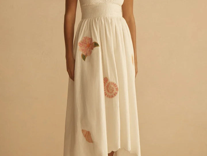 Woman wearing a white dress with floral details on a beige background