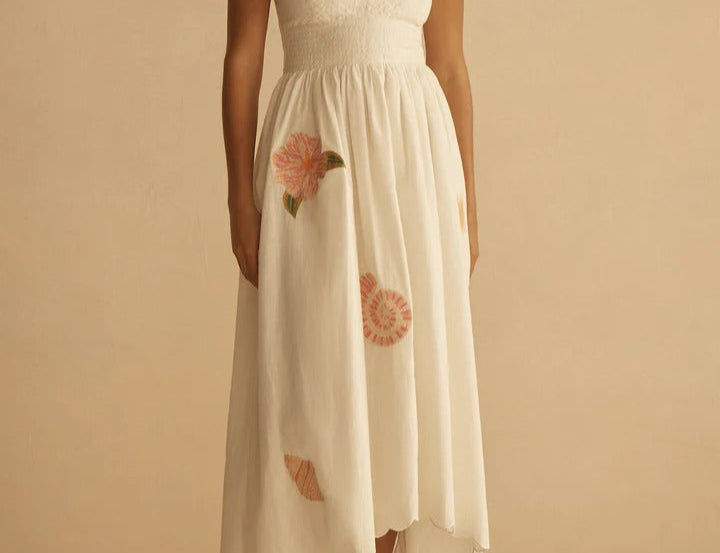 Woman wearing a white dress with floral details on a beige background