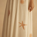 White dress with starfish and sun patterns on a beige background