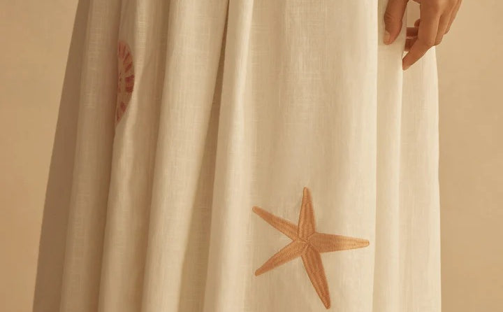 White dress with starfish and sun patterns on a beige background