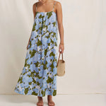 Woman wearing a floral dress holding a woven bag on a plain background