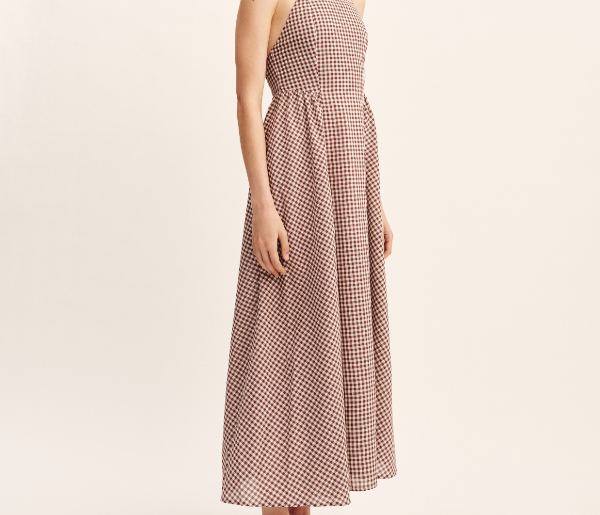 women wearing maxi Dress features a square neckline, elasticated back and free-flowing maxi skirt. It turns to reveal a statement open back with an adjustable tie feature. Mocha Gingham