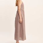 women wearing maxi Dress features a square neckline, elasticated back and free-flowing maxi skirt. It turns to reveal a statement open back with an adjustable tie feature. Mocha Gingham
