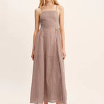 women wearing maxi Dress features a square neckline, elasticated back and free-flowing maxi skirt. It turns to reveal a statement open back with an adjustable tie feature. Mocha Gingham
