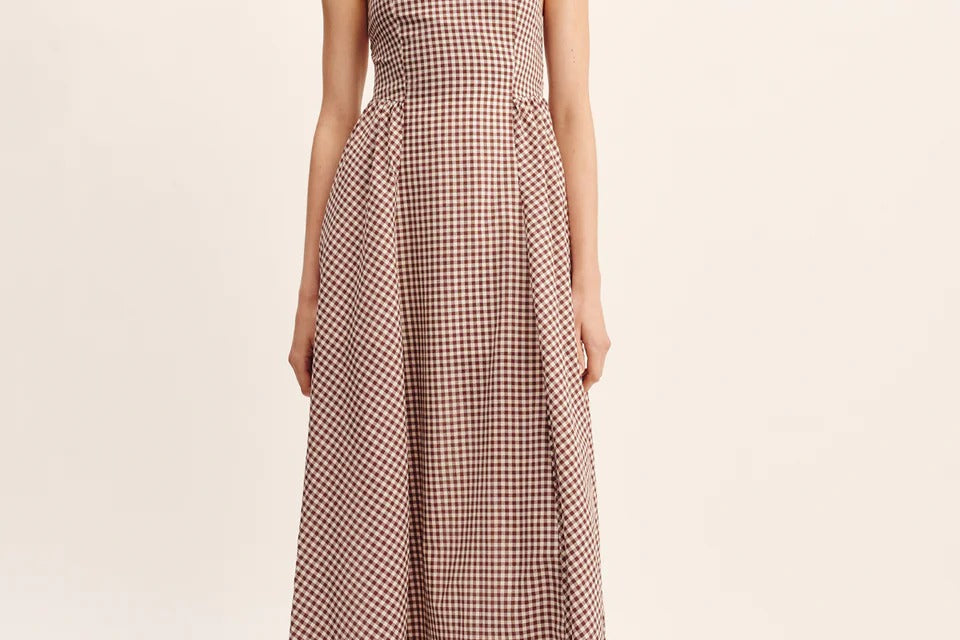 women wearing maxi Dress features a square neckline, elasticated back and free-flowing maxi skirt. It turns to reveal a statement open back with an adjustable tie feature. Mocha Gingham